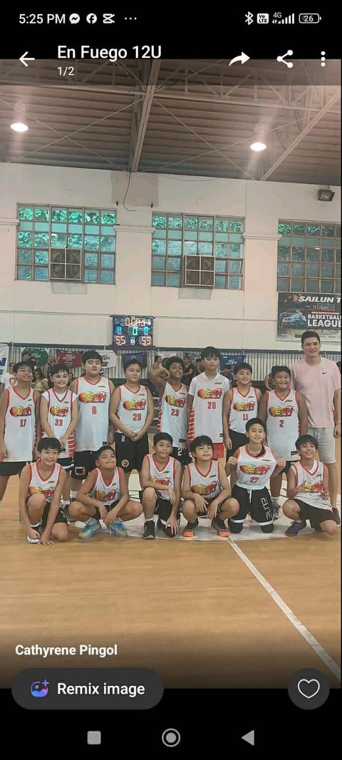 Youth basketball team En Fuego 12U posed together in matching white and orange jerseys inside an indoor gymnasium